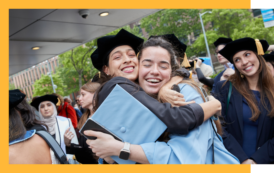students in cap and gown hugging